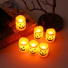 A collection of glowing LED skull and pumpkin candles arranged on a surface next to a dark branch.