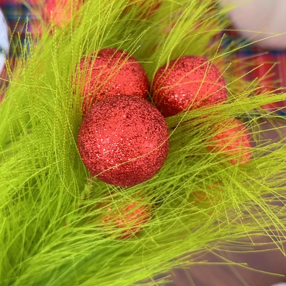 Red glitter spherical berries used as Christmas tree decor picks surrounded by bright green foliage