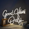 A glowing white neon sign spelling out Good Vibes Only against a dark background.