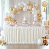 A white pleated polyester table skirt decorated with gold and white balloons and featuring a tiered cake display.
