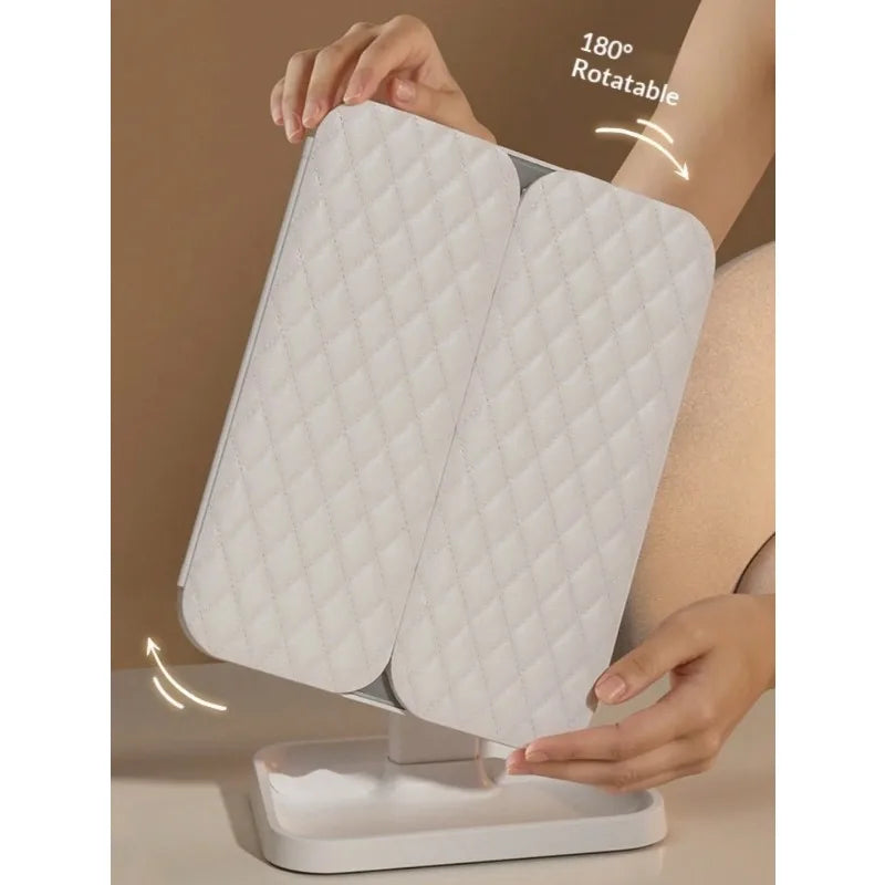 A person holds a white tri-fold LED makeup mirror with dimmable lighting, demonstrating its rotatable feature.