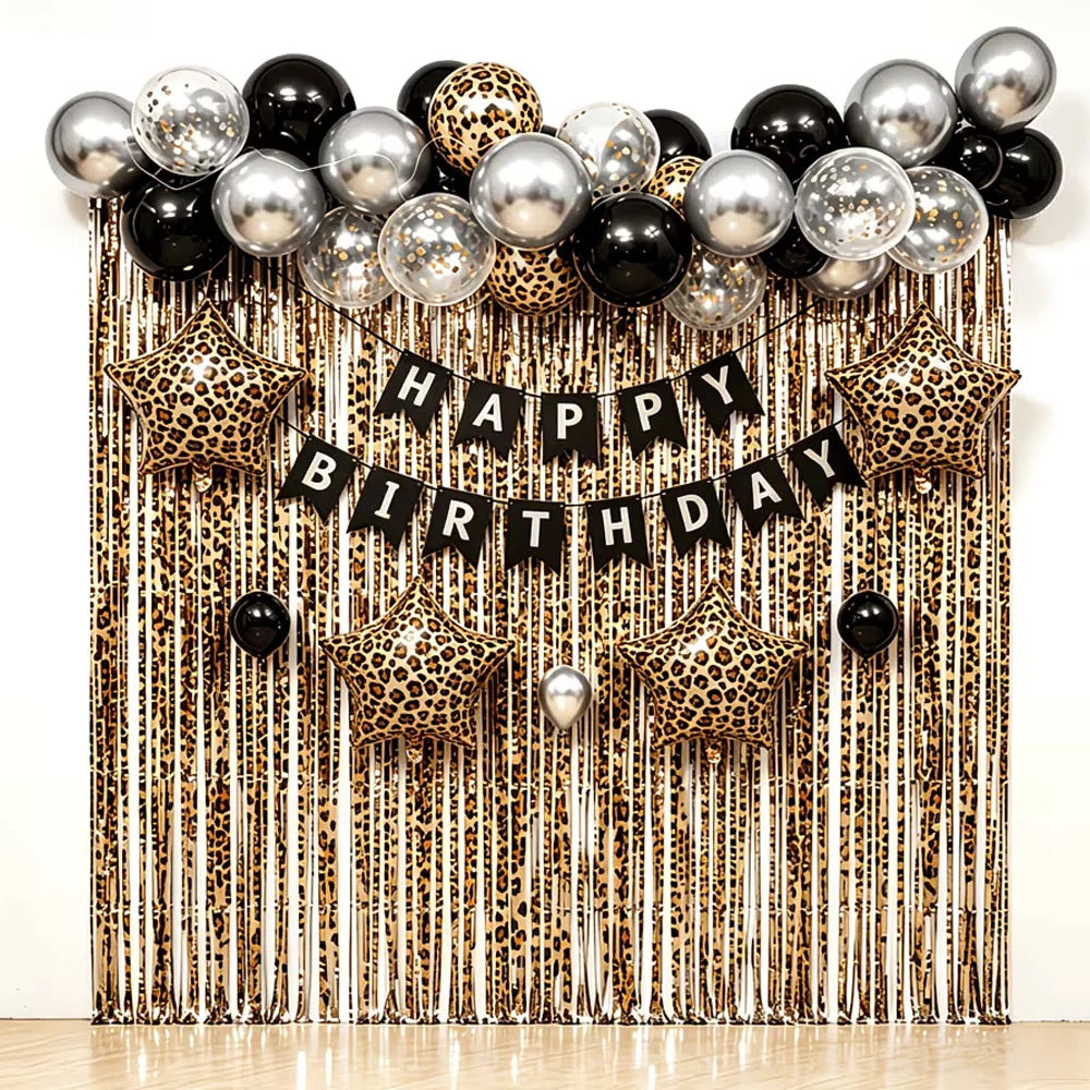 A festive birthday backdrop featuring leopard print balloons and a hanging tassel curtain.