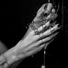 A close-up shot of a hand pouring liquid into a glass, with rings visible against a dark background.