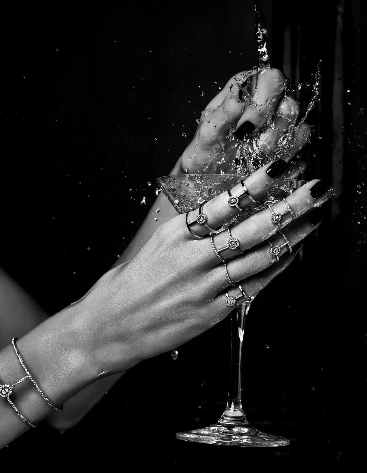 A close-up shot of a hand pouring liquid into a glass, with rings visible against a dark background.