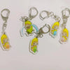 Acrylic keychain featuring a yellow cat with a banana and blue accents.