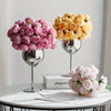 A display of silk peony bouquets in shades of pink and cream on a white table.