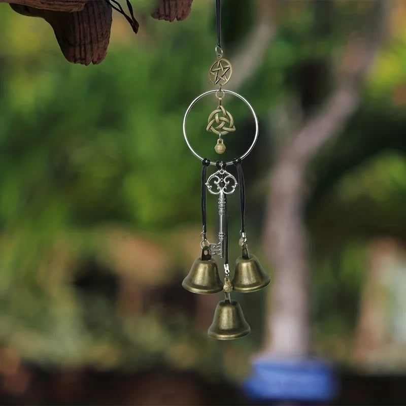A decorative witch bell wind chime hanging from a string, featuring a pentagram and small bells.