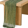 Sage green gauze table runner draped over a light wood table.
