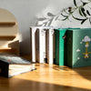 A set of green and white cartoon cover photo albums standing on a wooden surface with sunlight casting shadows.
