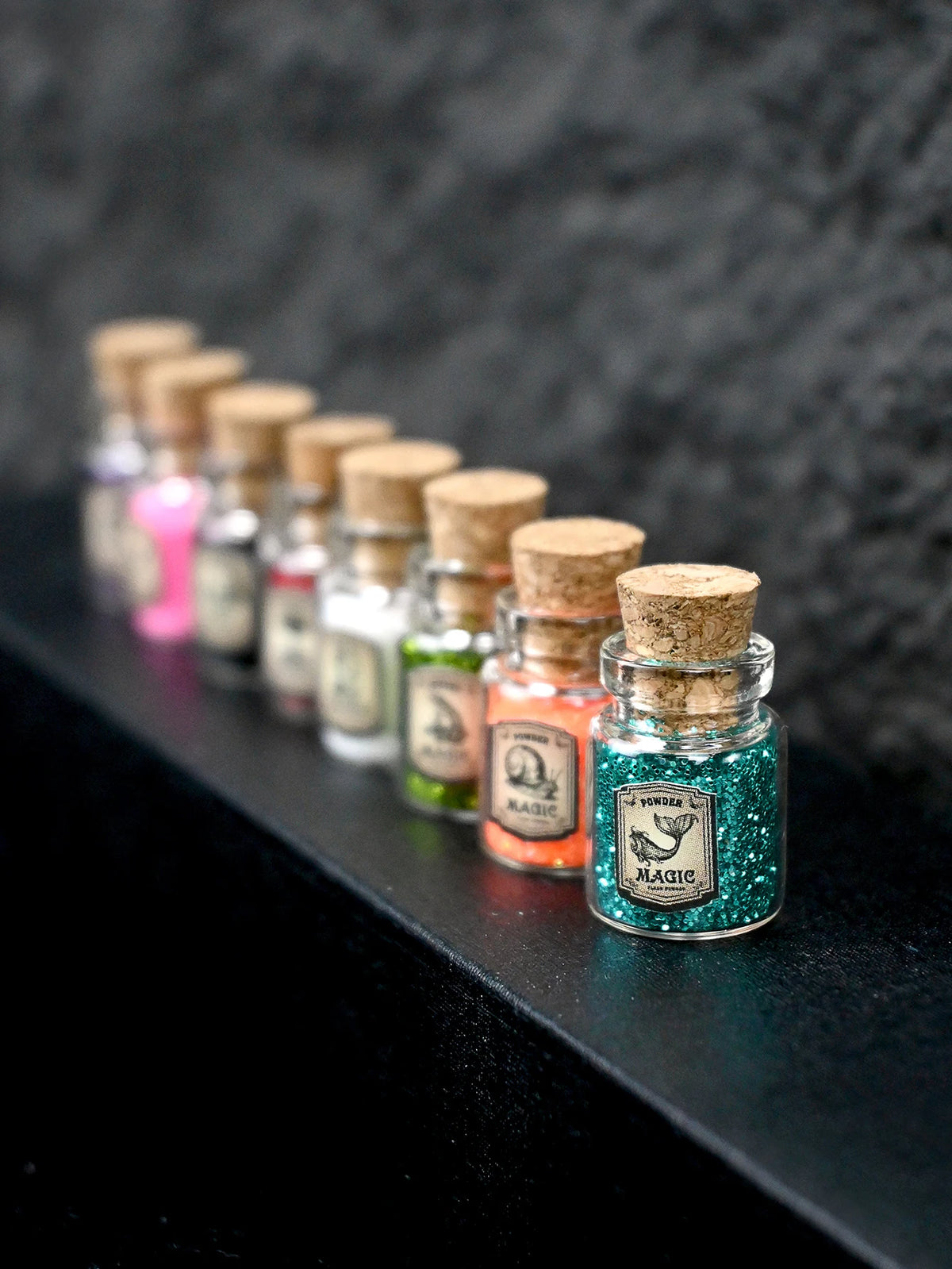 A row of small glass bottles filled with colorful glitter powder for party decorations