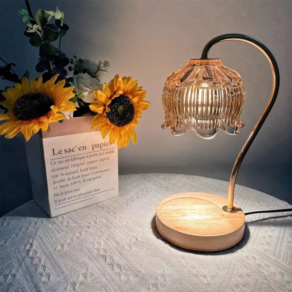 A glass decorative candle warmer lamp with a brass stand and amber-colored shade sits on a light surface next to a package of