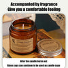 A glass jar candle labeled Aroma Sensation sitting on a wooden surface with a candle burning inside.