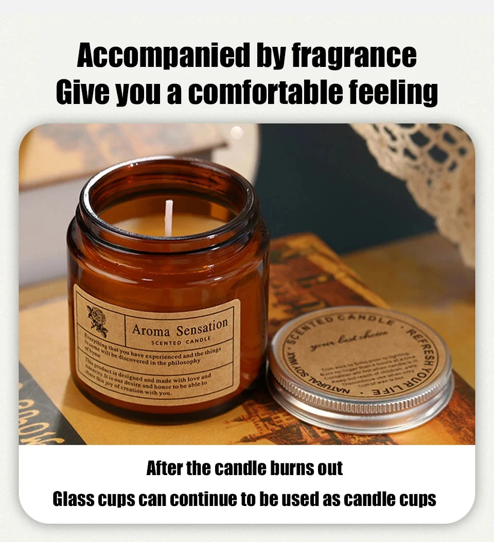 A glass jar candle labeled Aroma Sensation sitting on a wooden surface with a candle burning inside.