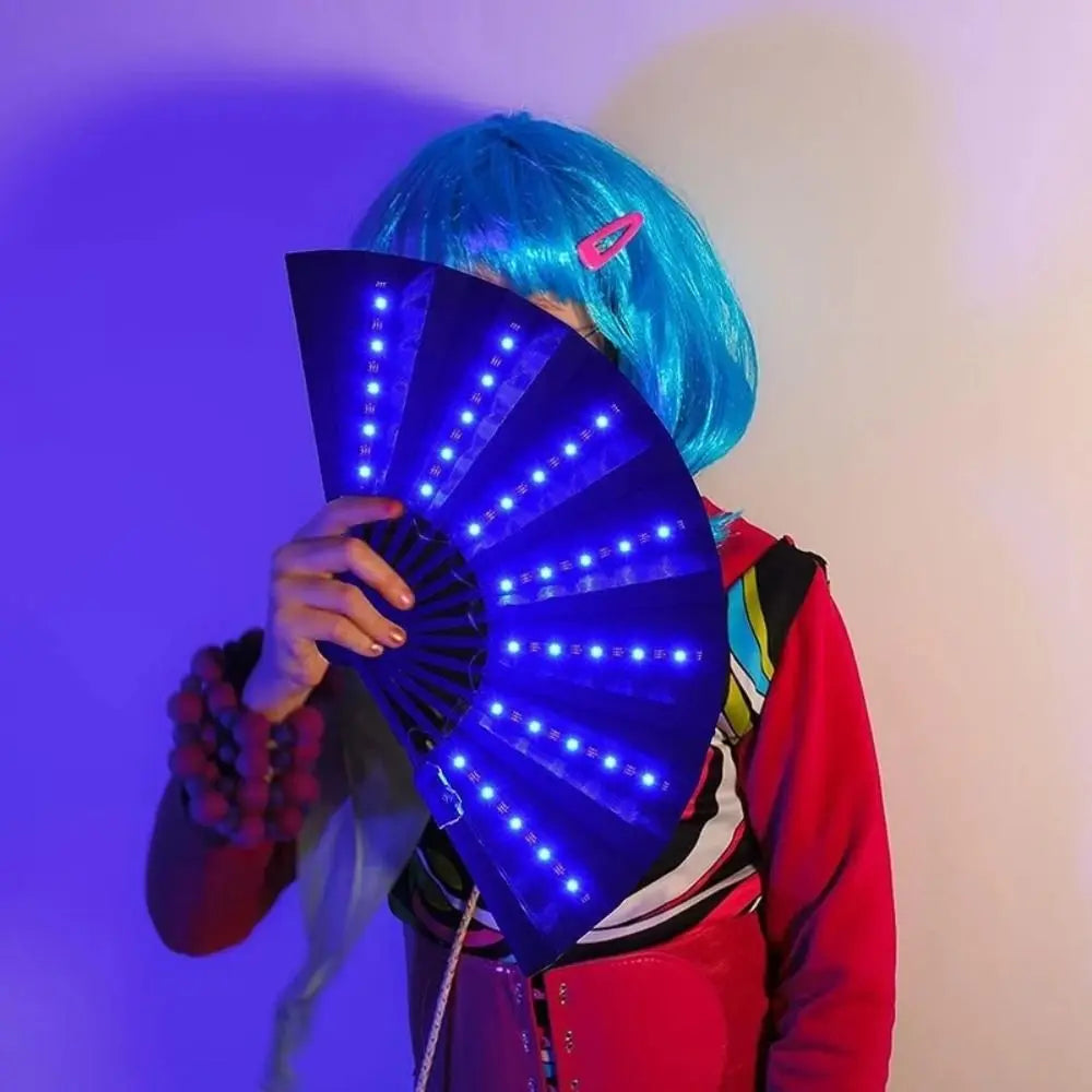 شخص يحمل مروحة ضوئية حريرية LED قابلة للطي تصدر ضوءًا أزرق على خلفية أرجوانية.