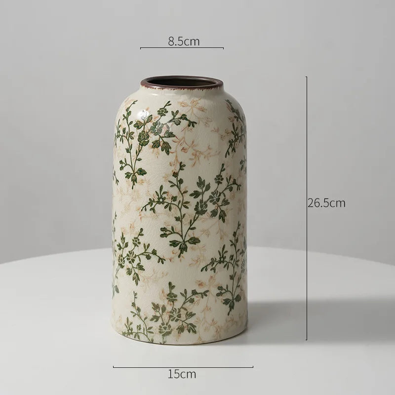 A tall ceramic milk pitcher with a cream background and green floral pattern, shown from the side.