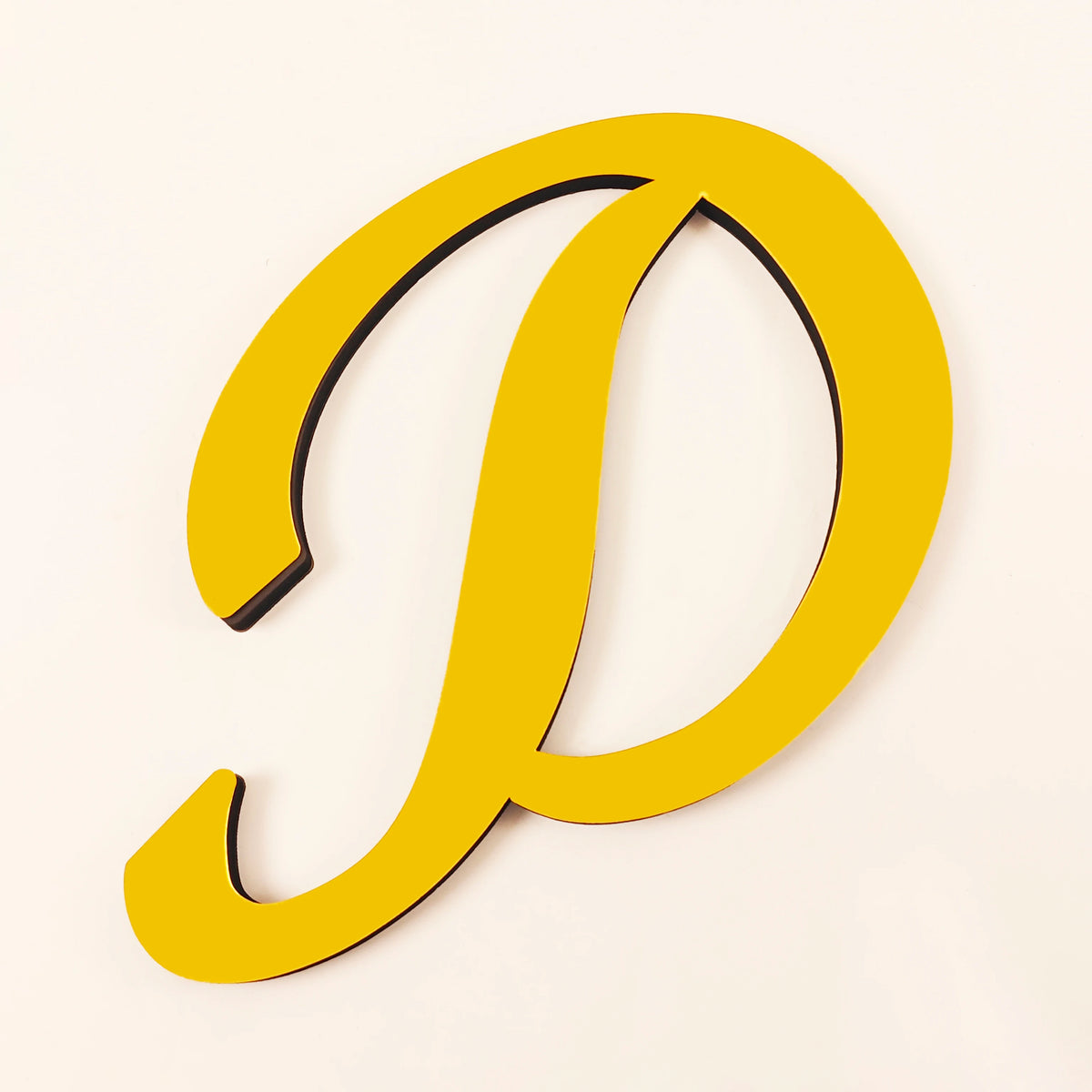 A yellow 3D acrylic letter D wall sticker with a black outline.