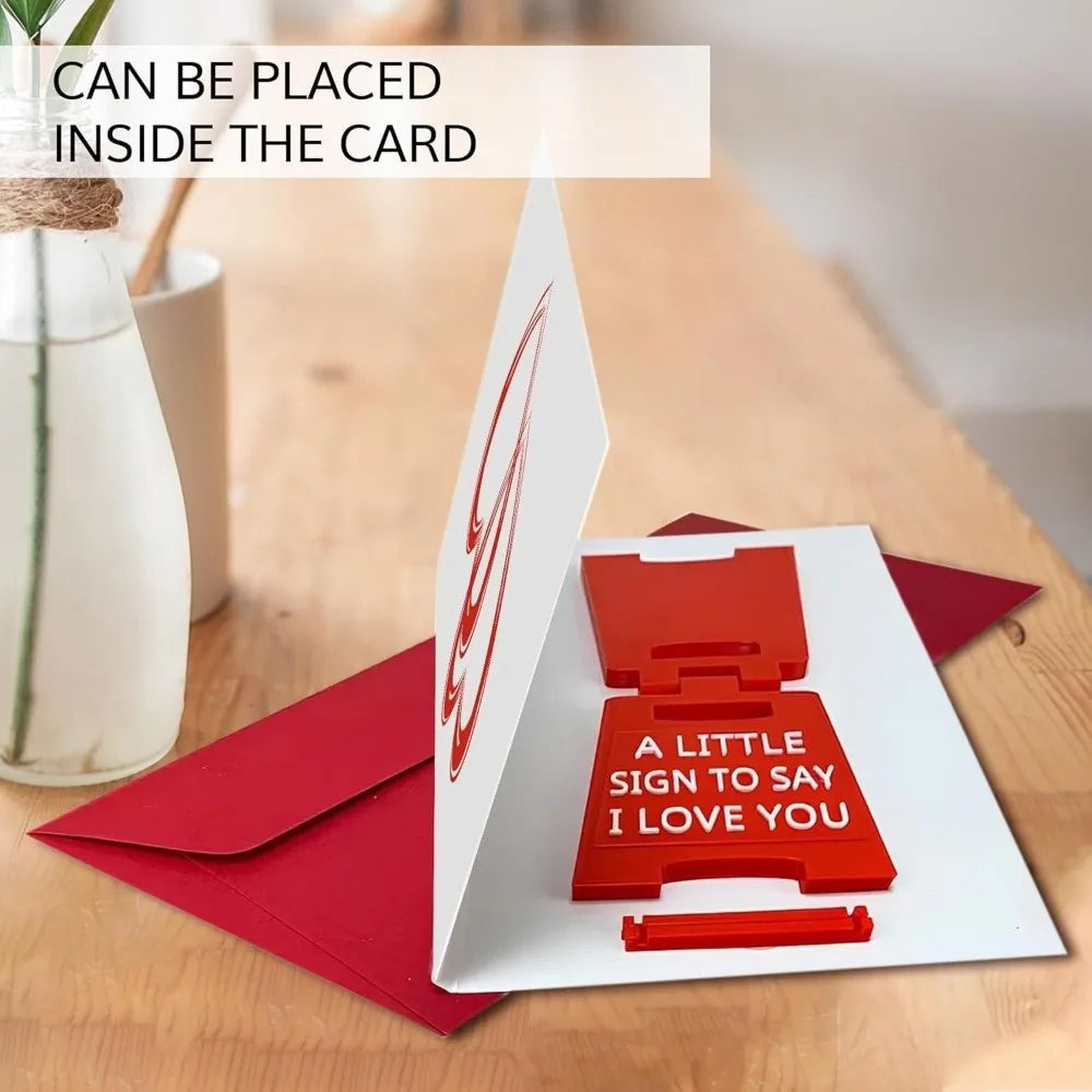 A red 3D printed letter sign to say I love you placed inside a white card.