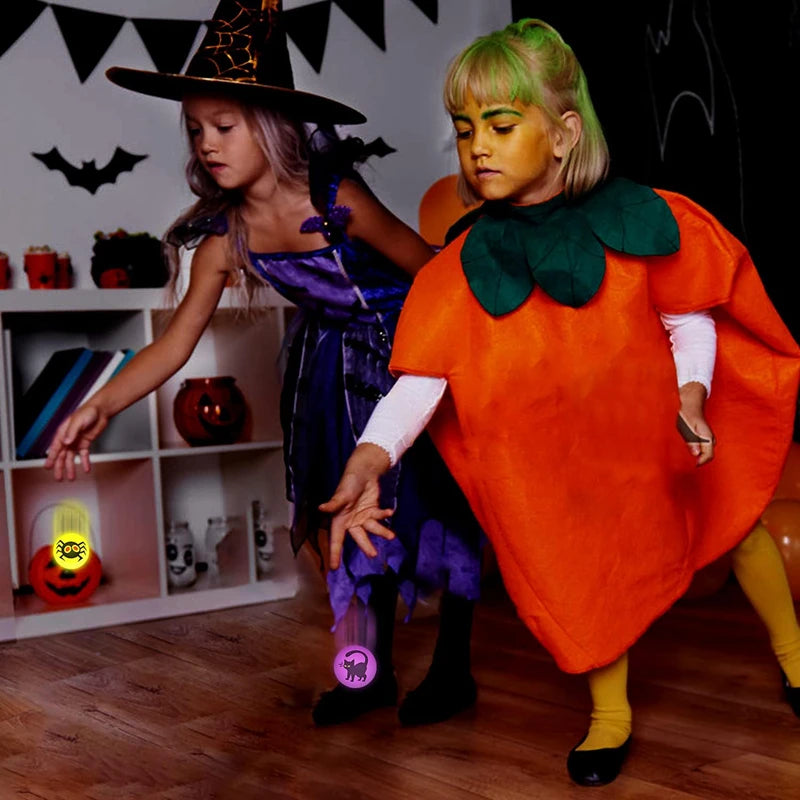 A young girl dressed in a purple witch costume stands next to an adult wearing an orange witch costume, both holding glow-in-