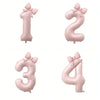 Four large pink foil number balloons shaped like 1, 2, 3, and 4 with bows