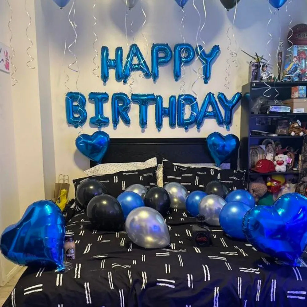 Blue foil letter balloons spelling HAPPY BIRTHDAY hanging above a bed