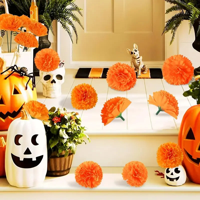A collection of bright orange and yellow artificial flower heads, including carnations and marigolds, displayed with pumpkins