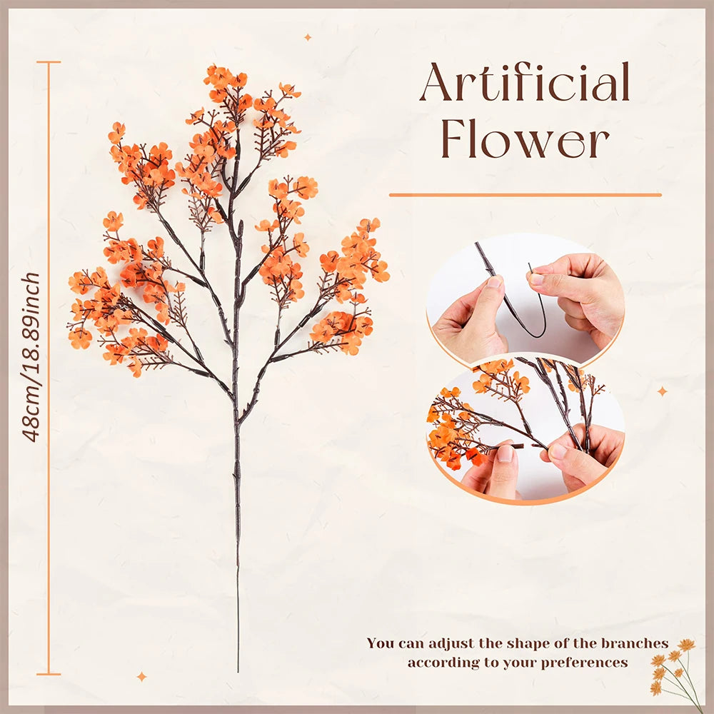 A sprig of artificial orange baby's breath flowers on a dark stem, shown with hands adjusting the branches.