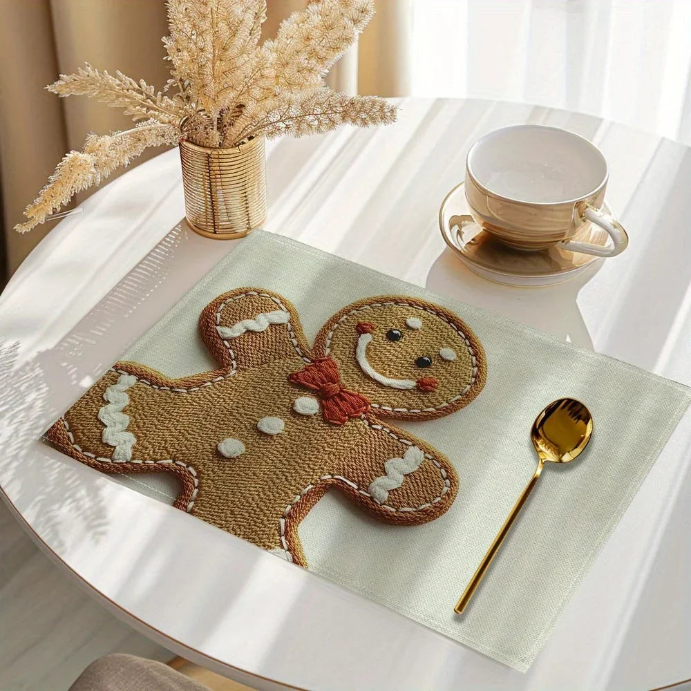 A set of four gingerbread man printed placemats on a light green table with a cup and a spoon.