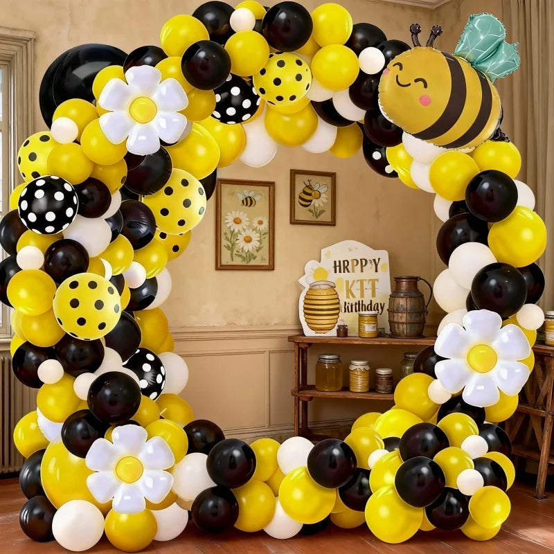 A colorful balloon arch set featuring yellow, black, and white balloons shaped like bees and daisies.