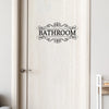 A white wooden door with an elegant black script sign reading BATHROOM.