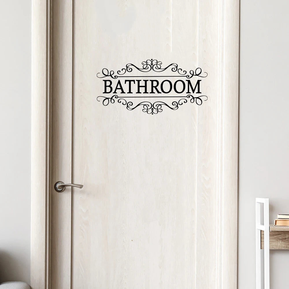 A white wooden door with an elegant black script sign reading BATHROOM.