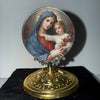 A painting of the Virgin Mary and the Christ Child in a halo set within a decorative gold-toned frame.