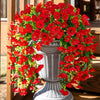 A vibrant red silk morning glory vine wreath with green leaves displayed in a gray urn for home decor.
