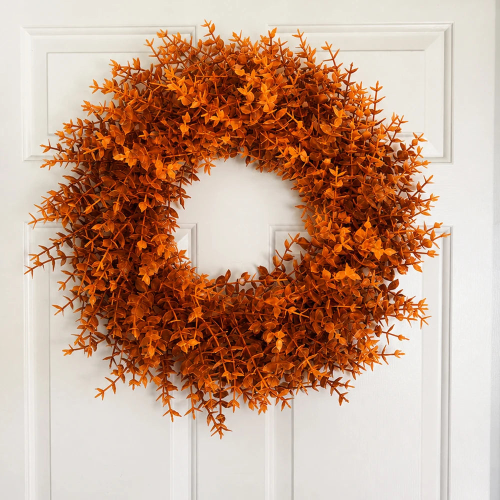 An artificial orange-brown eucalyptus wreath decorating a white front door.