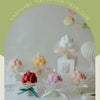 A collection of artisan tulip bouquet aromatherapy candles in various pastel colors like pink, yellow, and white.