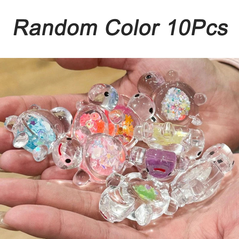 A hand holds a collection of 10 glow-in-the-dark mini sea turtle figurines in various colors for crafts and decor.