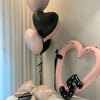 A display of heart-shaped balloons in pink and black, including a large balloon and a heart-shaped frame.