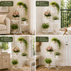 A white metal corner plant stand displaying various potted plants and flowers in a living room setting.