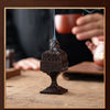 A dark bronze incense burner crafted with ingenuity sits on a wooden surface.