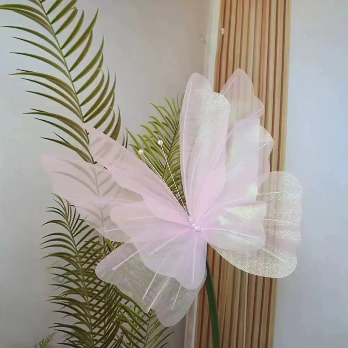 Pink sheer fabric butterfly wall decor featuring delicate petals and green foliage.
