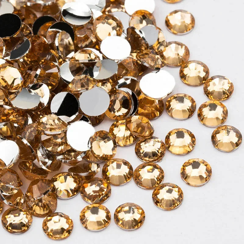A pile of round flatback resin rhinestones in gold and silver tones for crafts and nail art
