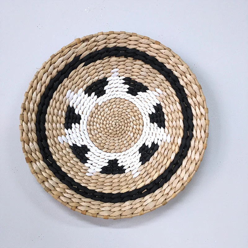 Round woven straw wall decor hanging with concentric black and white patterns