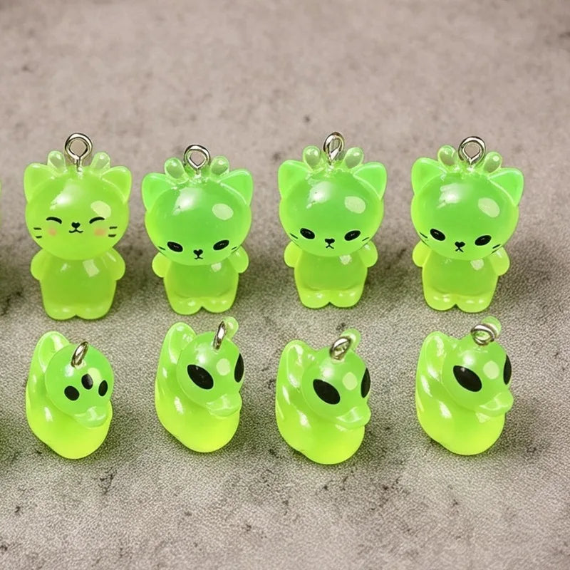 A set of six glow-in-the-dark resin charms shaped like cartoon kitty ducks with ears and a small nose.