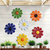 A collection of colorful iron sunflower wall art decor featuring orange, green, white, and blue flowers mounted on a white wo