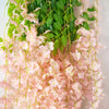 Pink silk wisteria vine garland with green leaves used for weddings and home decor