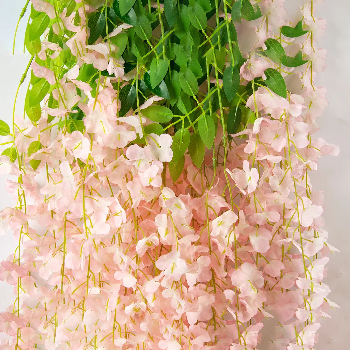 Pink silk wisteria vine garland with green leaves used for weddings and home decor