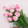 A bouquet of pink and white artificial tulips arranged in green leaves.