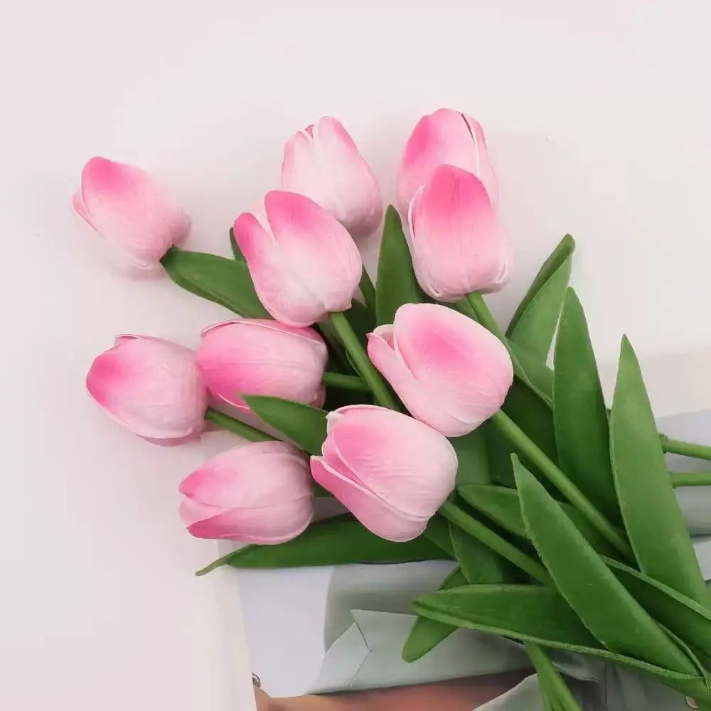 A bouquet of pink and white artificial tulips arranged in green leaves.