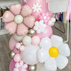 A large arrangement of pink and white floral balloons, including a pillar balloon, is displayed on a white table.