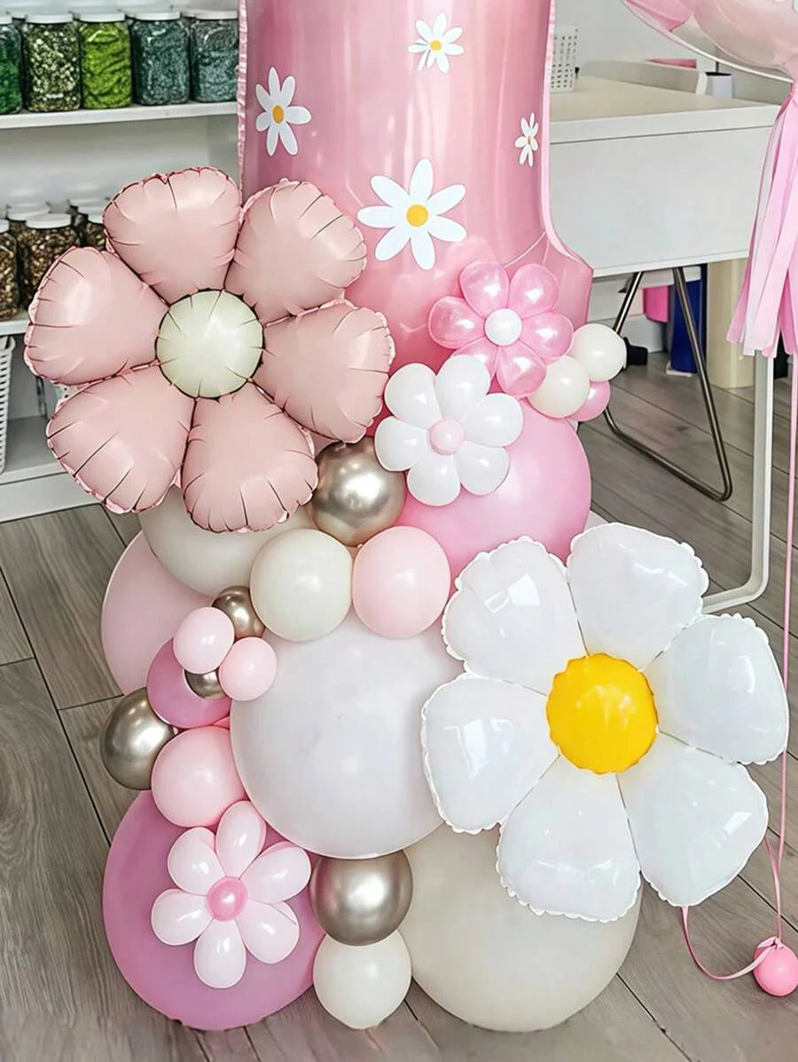 A large arrangement of pink and white floral balloons, including a pillar balloon, is displayed on a white table.