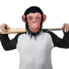 A person wearing a latex monkey mask costume with reddish-brown skin and black hair, holding a wooden stick.